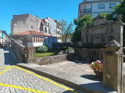 a city street with a stone wall and flowers at Fogar da Fraga in Caldas de Reis