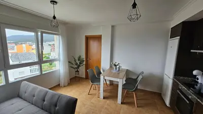 a living room with a table and chairs and a couch at Apartamento Faro Burela in Burela de Cabo