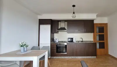 a kitchen with brown cabinets and a table and a table and a table at Apartamento Faro Burela in Burela de Cabo