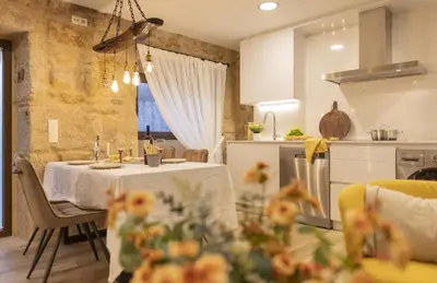 a kitchen and a dining room with a table and chairs at O Fogar da Pequena Galia in Caldas de Reis