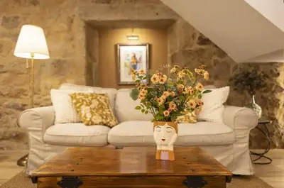 a vase of flowers on a coffee table in a living room at O Fogar da Pequena Galia in Caldas de Reis