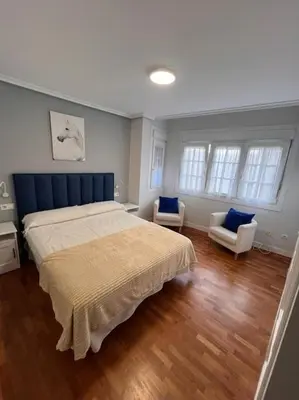 a bedroom with a large bed and two chairs at Casa con terraza en el casco in Betanzos