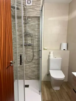 a bathroom with a toilet and a glass shower at Casa con terraza en el casco in Betanzos