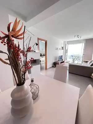 a white vase with flowers on a table in a living room at S&H La Gaita in Foro