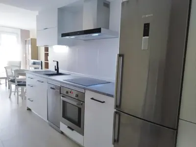 a kitchen with white cabinets and a stainless steel refrigerator at Apartamento 
