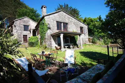 a stone house with a table and chairs in front of it at Te Cuento 3 Xesteira in A Xesteira