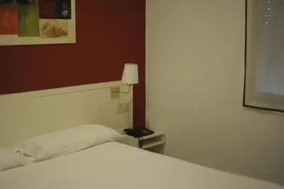 a bedroom with a bed and a lamp on a table at Hotel Miño in Ourense