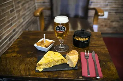 a table with a glass of beer and a slice of pizza at Hotel Miño in Ourense