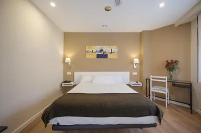 a bedroom with a large bed and a chair at Hotel Miño in Ourense
