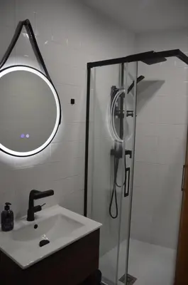 a bathroom with a sink and a shower with a mirror at Tras Do Atrio Casa en el Centro de Betanzos in Betanzos