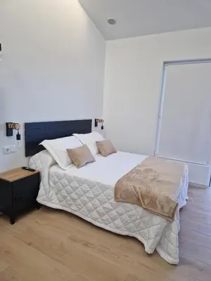 a bedroom with a large bed with white sheets and pillows at Apartamentos Pasiño in Portomarin