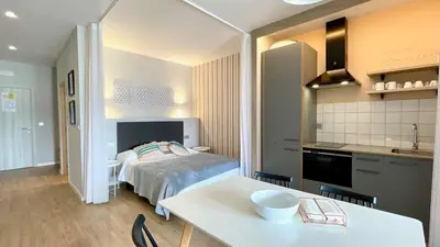 a bedroom with a bed and a table and a kitchen at The Cliffs A Ribeira - Pampillosa in Foz