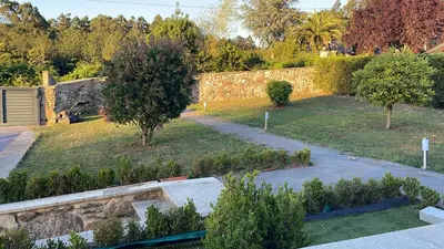 a garden with two trees and a stone wall at Casa vanguardista en el campo cerca de Santiago in Pontevedra