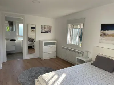 a white bedroom with a bed and a bathroom at Casa vanguardista en el campo cerca de Santiago in Pontevedra
