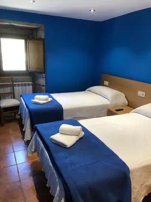 a room with three beds with blue walls and towels at Casa do Ferreiriño in Chacente