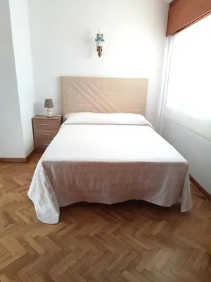 a bedroom with a large white bed with a wooden floor at Pensión La Plaza in Betanzos