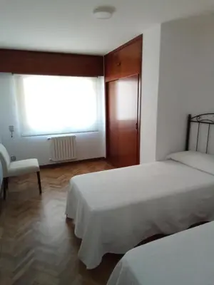 a bedroom with two beds and a window at Pensión La Plaza in Betanzos