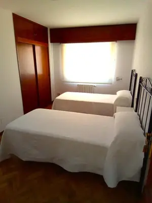 two beds in a room with a window at Pensión La Plaza in Betanzos