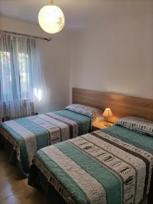a bedroom with two beds and a chandelier at Casa la Camila in Tapia de Casariego
