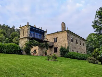 an old brick building with a tower on a grass field at Casa Doñano in Ribadeo