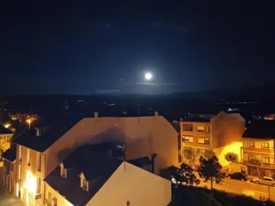 a view of a city at night with a full moon at La Tebaida in Ponferrada