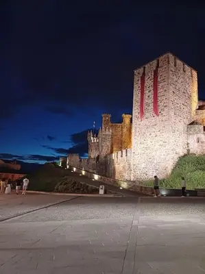 a castle at night with people walking in front of it at La Tebaida in Ponferrada