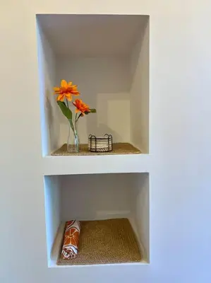a white shelf with a vase with a flower in it at A Casiña do Rey Casita junto a la playa de Cabañas in Cabañas