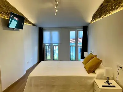 a bedroom with a large bed with a tv on the wall at A Casiña do Rey Casita junto a la playa de Cabañas in Cabañas