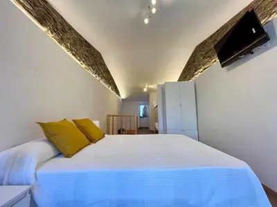 a bedroom with a large white bed with yellow pillows at A Casiña do Rey Casita junto a la playa de Cabañas in Cabañas