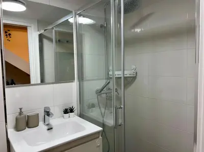 a white bathroom with a shower and a sink at A Casiña do Rey Casita junto a la playa de Cabañas in Cabañas
