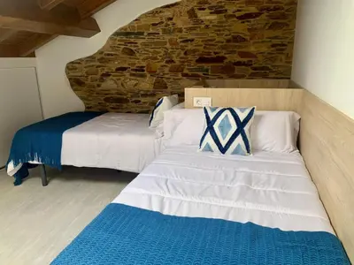a bedroom with two beds and a brick wall at Amencer en Llas in Foz