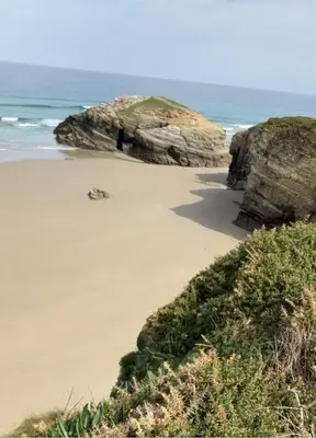 a beach with a large rock and the ocean at Apartamento Playa las catedrales in Foro