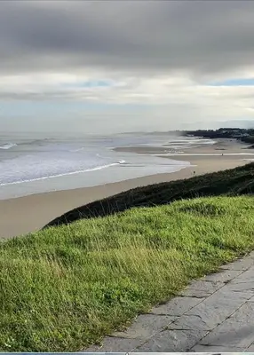 a beach with people walking on the sand and the ocean at Apartamento Playa las catedrales in Foro