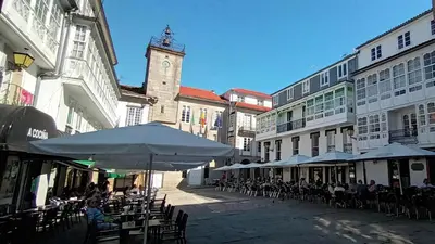 a street with tables and chairs and a clock tower at Adiva Suite in Puentedeume