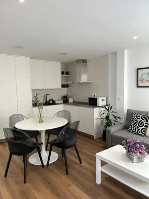 a living room with a table and chairs and a kitchen at Adiva Suite in Puentedeume