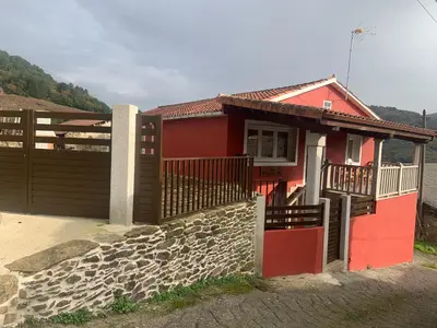 a red house with a gate and a stone wall at Casa do Feligrés e da Alsira in Nogueira