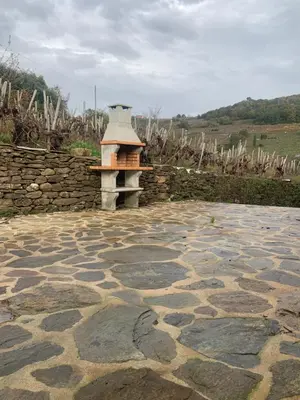 a stone patio with a stone wall and a bird house at Casa do Feligrés e da Alsira in Nogueira