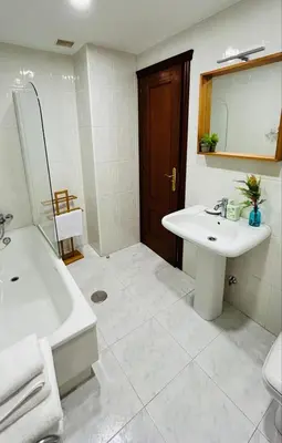 a white bathroom with a sink and a tub and a mirror at Duplex Olas de Ribadeo in Ribadeo