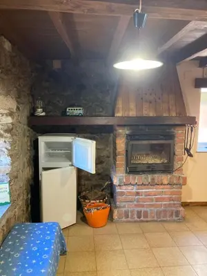 a kitchen with a brick fireplace and a refrigerator at Somiedoeco in Caunedo