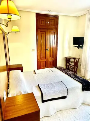 a bedroom with a large white bed and a table at Hostal La Cubana in Carballino