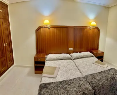 a bedroom with a large bed and a wooden headboard at Hostal La Cubana in Carballino