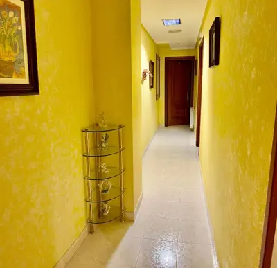 a hallway with yellow walls and a shelf with glasses at Hostal La Cubana in Carballino