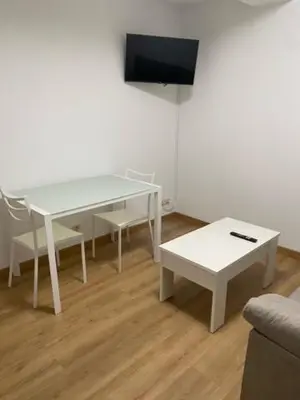a living room with a white table and a tv at o piso de loli e manolo in Santiago de Compostela