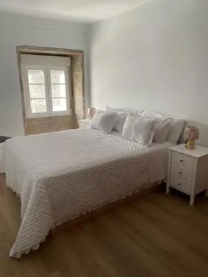 a bedroom with a large bed with white sheets and a window at o piso de loli e manolo in Santiago de Compostela