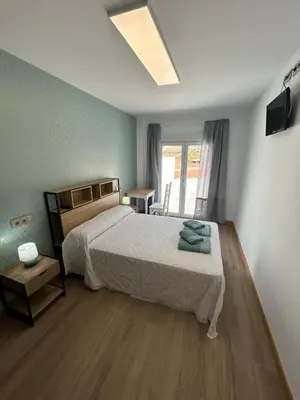 a bedroom with a bed and a table and a window at Apartamentos Torres del Milladoiro in Amés