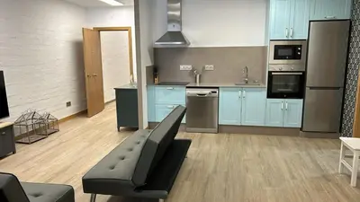 a large kitchen with blue cabinets and a black couch at Apartamentos Torres del Milladoiro in Amés
