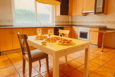 a kitchen table with two plates of food and wine glasses at Casa Vixoi, a 5Km Catedral in Santiago de Compostela