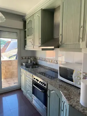 a kitchen with white cabinets and a sink and a microwave at O piso de Cris in Caldas de Reis