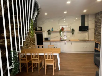 a kitchen with a wooden table and chairs in a room at Boutique Vila de Triacastela in Tríacastela