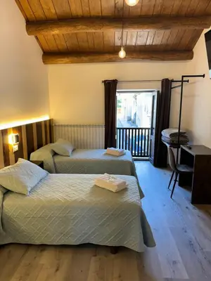 a room with two beds and a desk and a window at Boutique Vila de Triacastela in Tríacastela